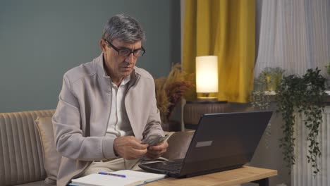 Anciano-Mirando-Una-Computadora-Portátil-Contando-Dinero.